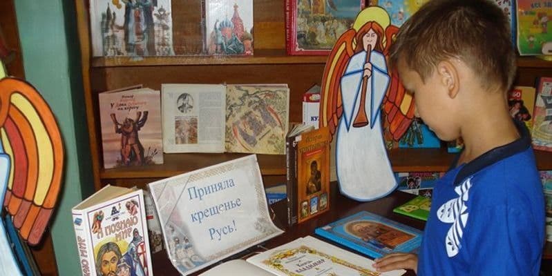 Хлопчик біля бібліотечної виставки про Хрещення Русі. Фото: Telegram/Центр національного спротиву