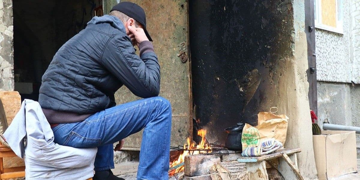 <em>Чоловік біля вогнища у дворі багатоповерхівки у Костянтинівці, 31 жовтня 2025 року. Фото: НПУ</em>