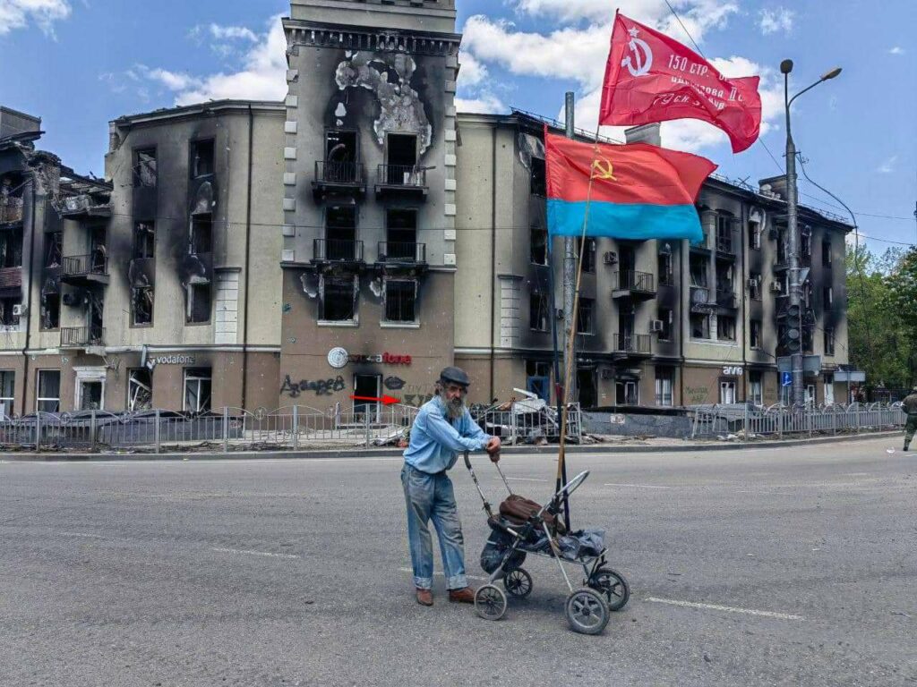 Смотрите не на городского сумасшедшего, а на надпись сзади на доме, где раньше жила замечательная мариупольская журналистка Алевтина Швецова. Ранее дома в центре города не были обрисованы, поэтому надпись «путин хуйло» появилась там точно недавно. Мариуполь непобедим